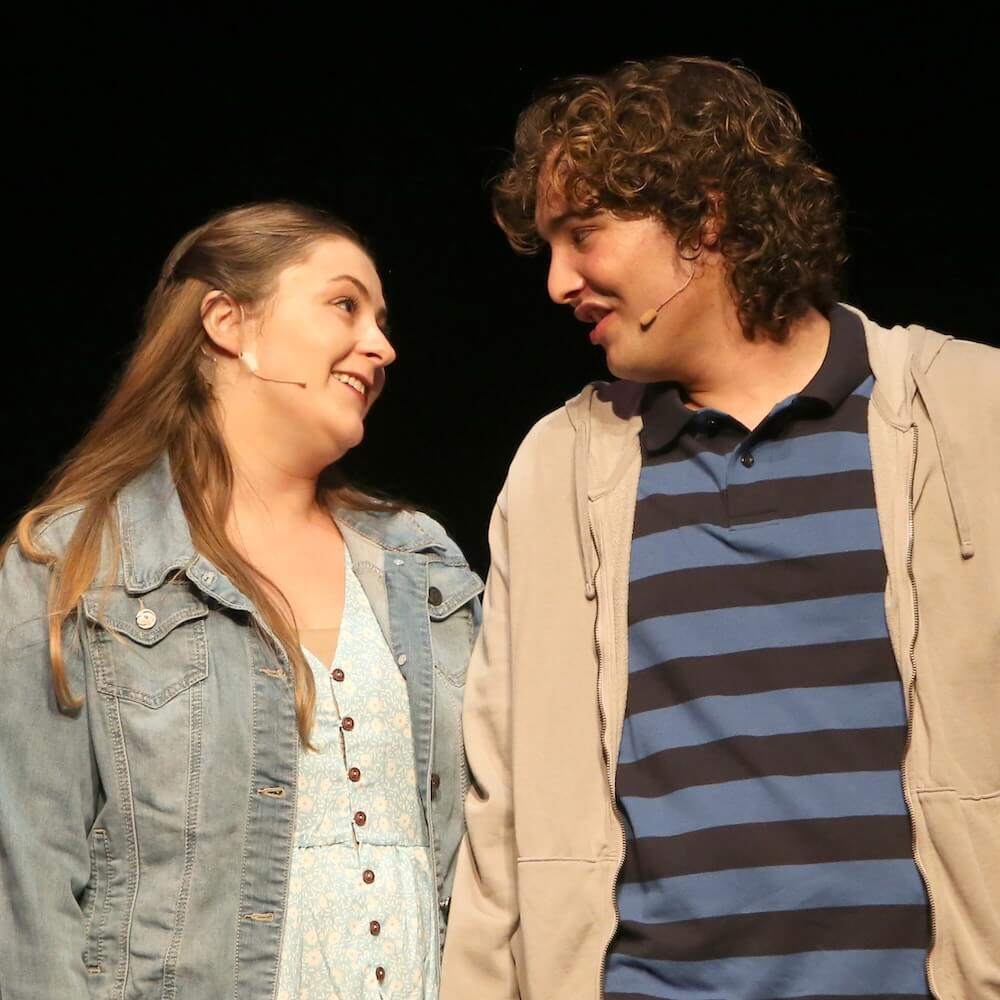 Two actors singing to each other with smiling faces